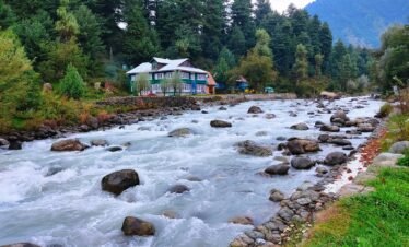 Kashmir tour package – houseboat on Dal Lake with snow-capped Himalayas at sunrise