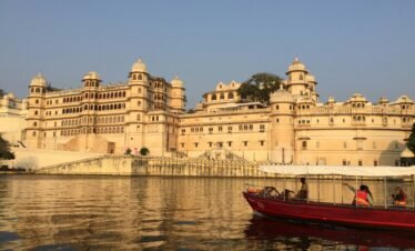 Udaipur Mount Abu tour — City Palace Udaipur illuminated at night with reflection on Lake Pichola