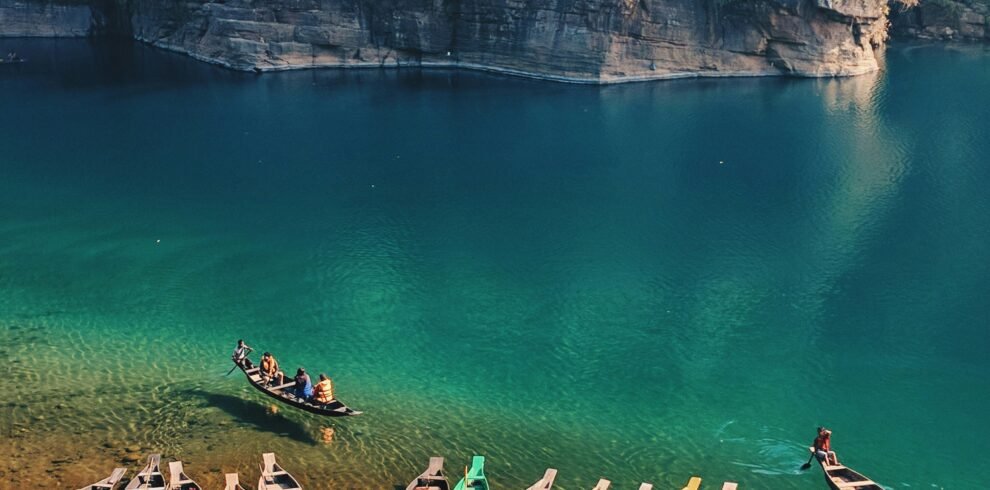 Boats floating on the crystal-clear Umngot River at Dawki, Meghalaya, with transparent water revealing the riverbed below