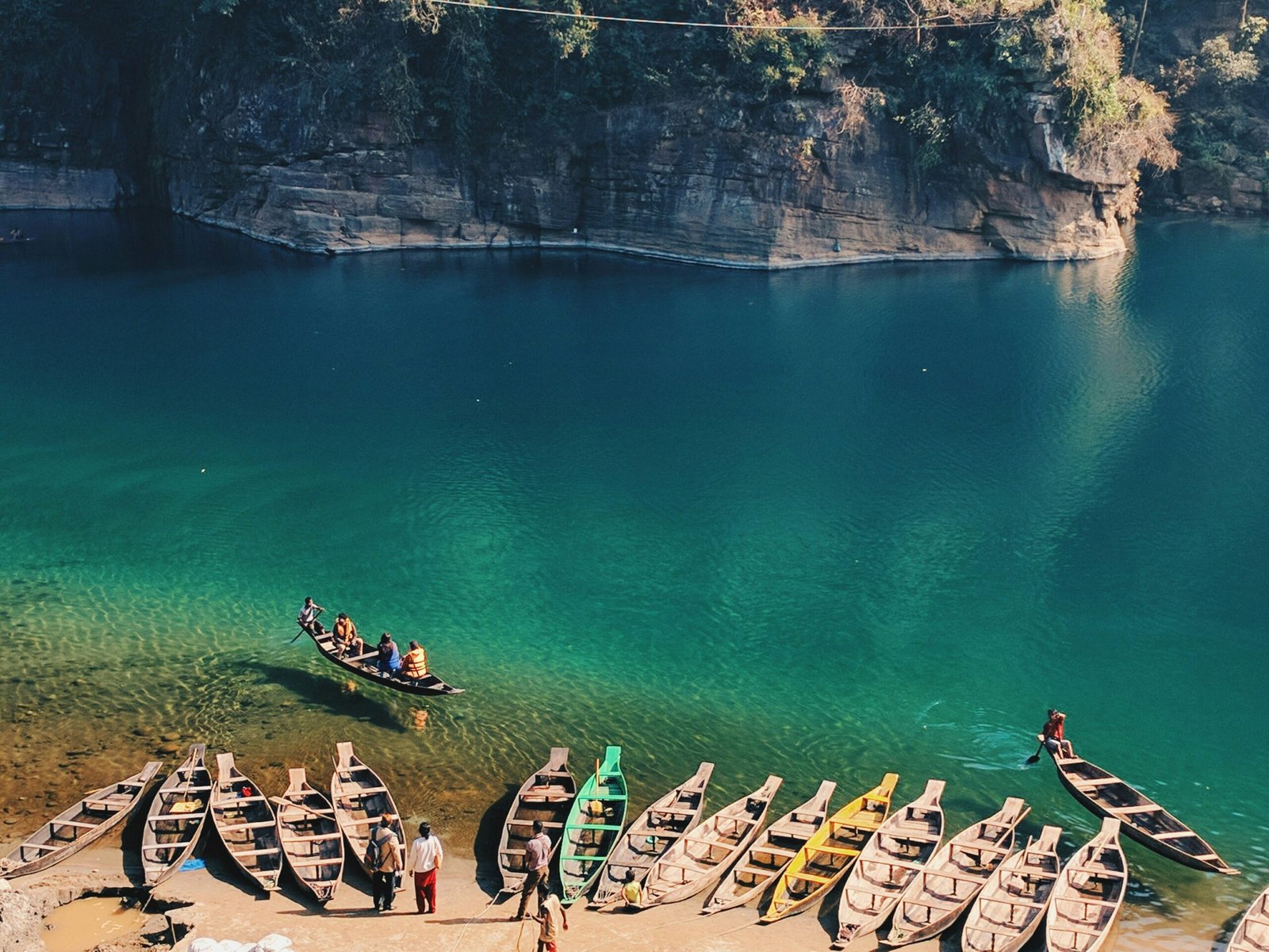 Boats floating on the crystal-clear Umngot River at Dawki, Meghalaya, with transparent water revealing the riverbed below