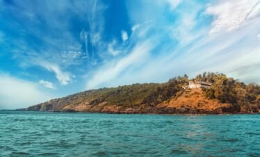 Budget Goa package — Baga Beach North Goa golden shore palm trees tourists and beach shacks aerial view